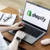 Una donna al computer con logo di Shopify al centro dello schermo