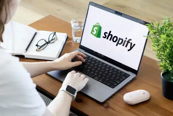 Una donna al computer con logo di Shopify al centro dello schermo